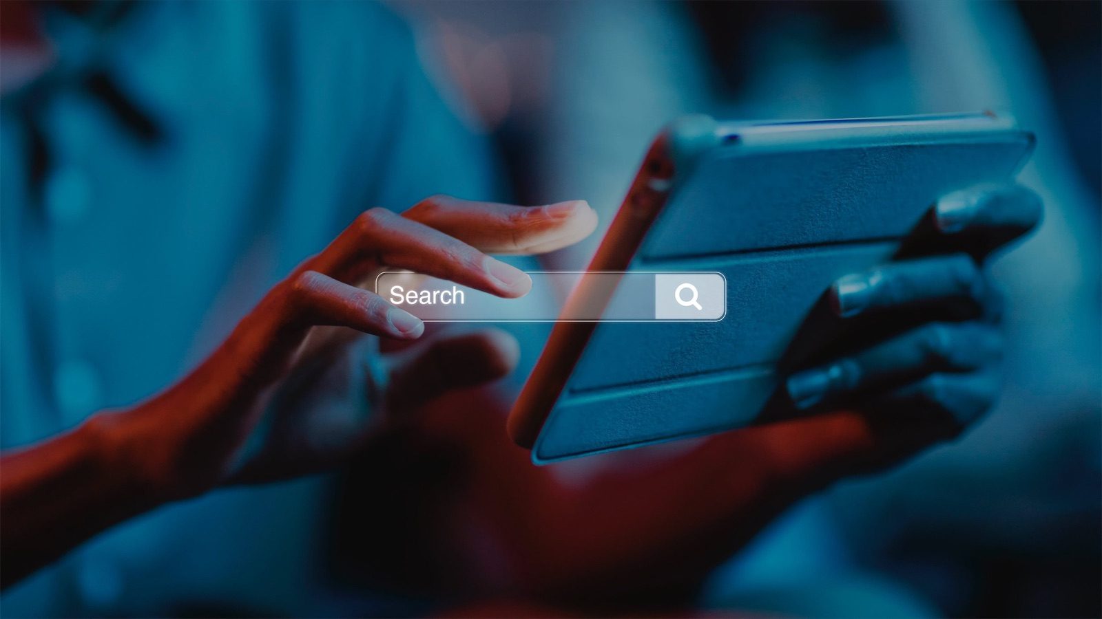 Una mano sfiora una barra di ricerca luminosa davanti a un tablet, in luce blu e rossa