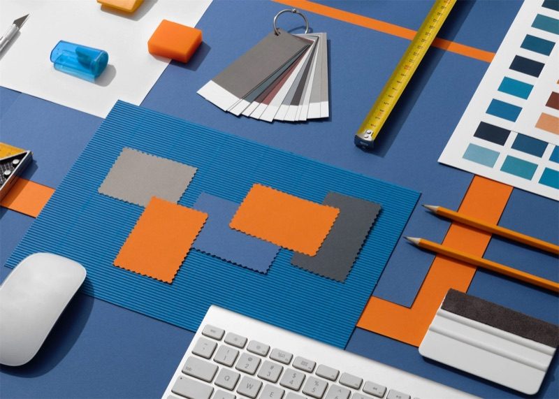 Campionari di colore, metro, matite e ritagli arancio su un tavolo blu