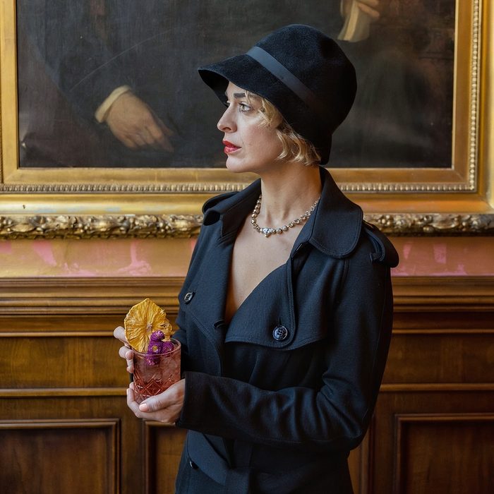 Una donna col cappello e un bicchiere davanti a un quadro, shooting per Caffè Rivoire