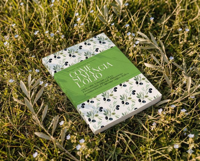 Il libro Come si mangia l’olio appoggiato sull’erba fra i rami d’ulivo