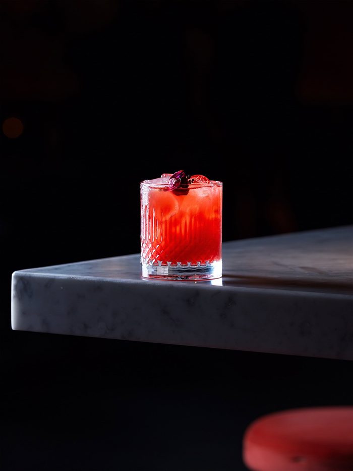 Un cocktail rosso sul bancone scuro del MAG 56 di Prato