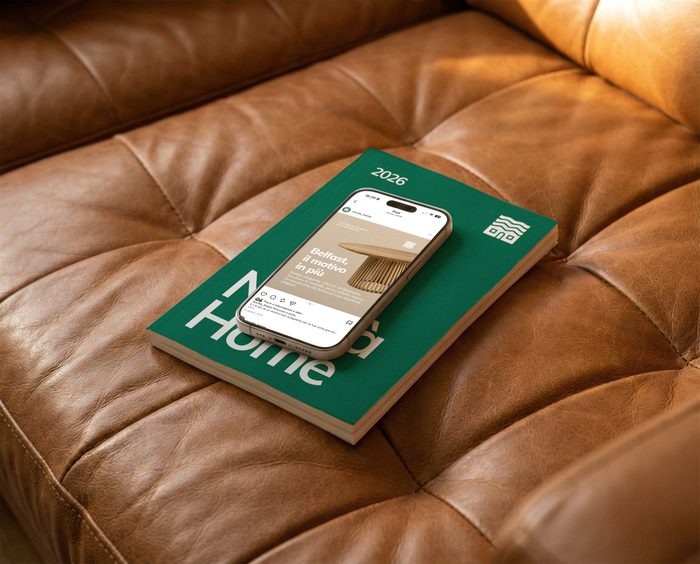 Catalogo e telefono con il sito di Novità Home su un divano in pelle