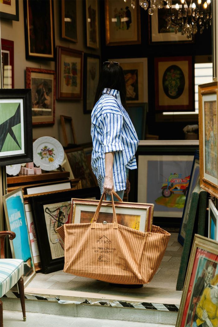 Borsa e oggetti Puebco in una bottega piena di quadri e cornici
