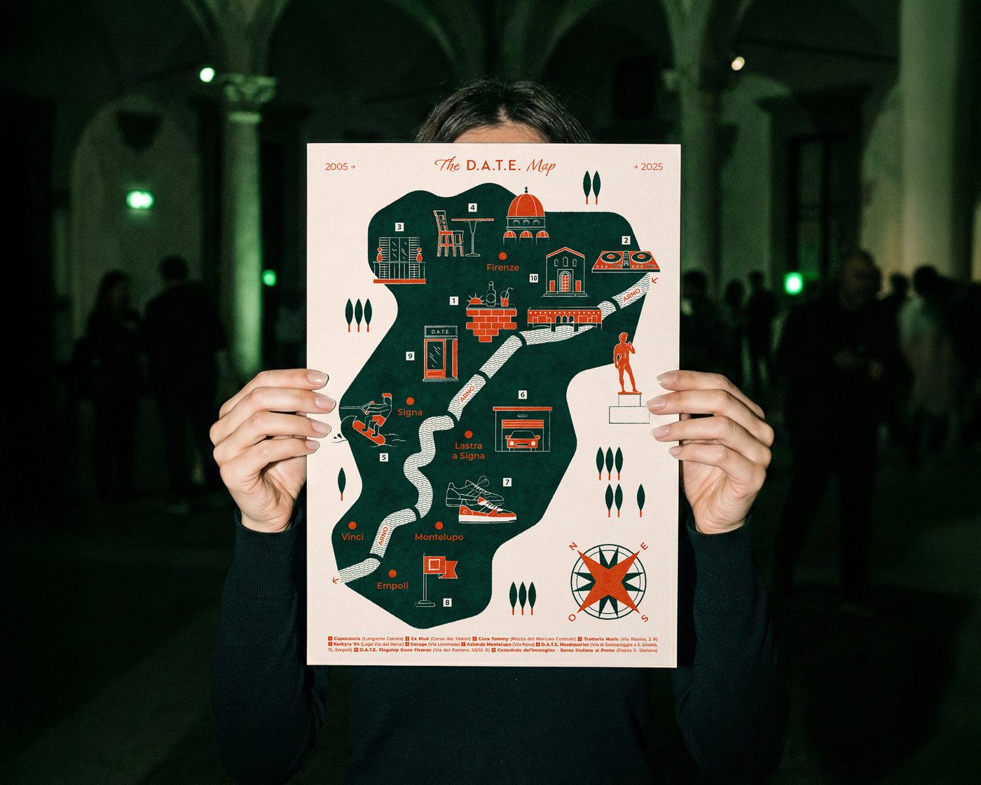 La mappa dei vent’anni di D.A.T.E. aperta fra due mani, su fondo verde scuro