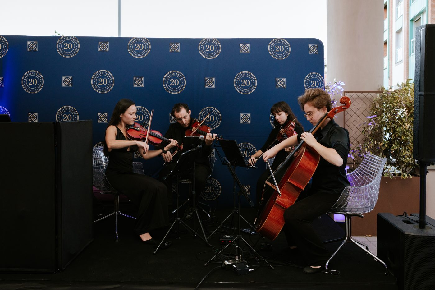 Il quartetto d’archi suona davanti al fondale blu coi sigilli di Chapter 20