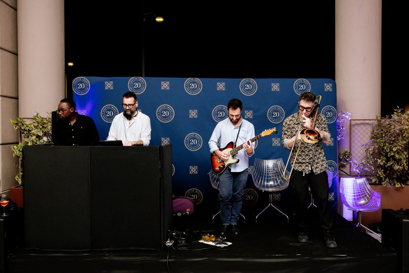 La band e il DJ sul palco, davanti al fondale del ventennale