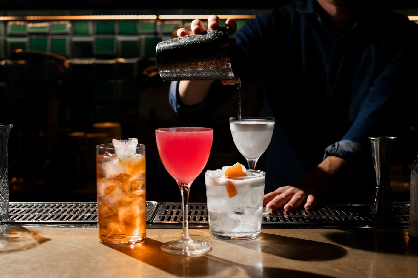 Tre cocktail sul bancone di Amedeo, davanti alle piastrelle verdi
