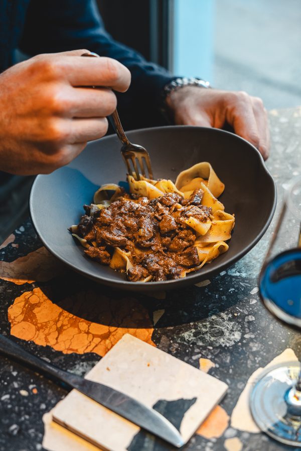 Una forchetta affonda in un piatto di pasta scuro
