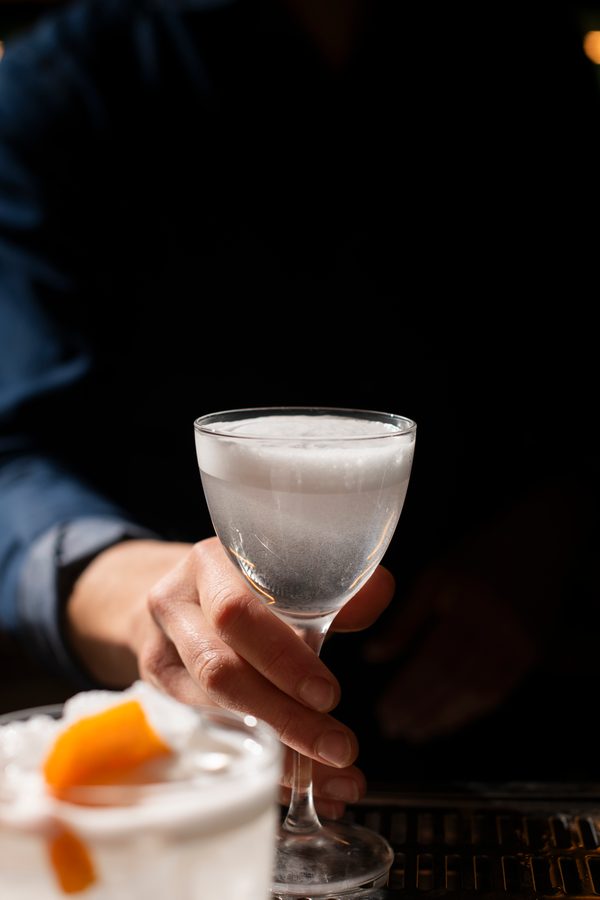 Una mano tiene un calice con un cocktail bianco