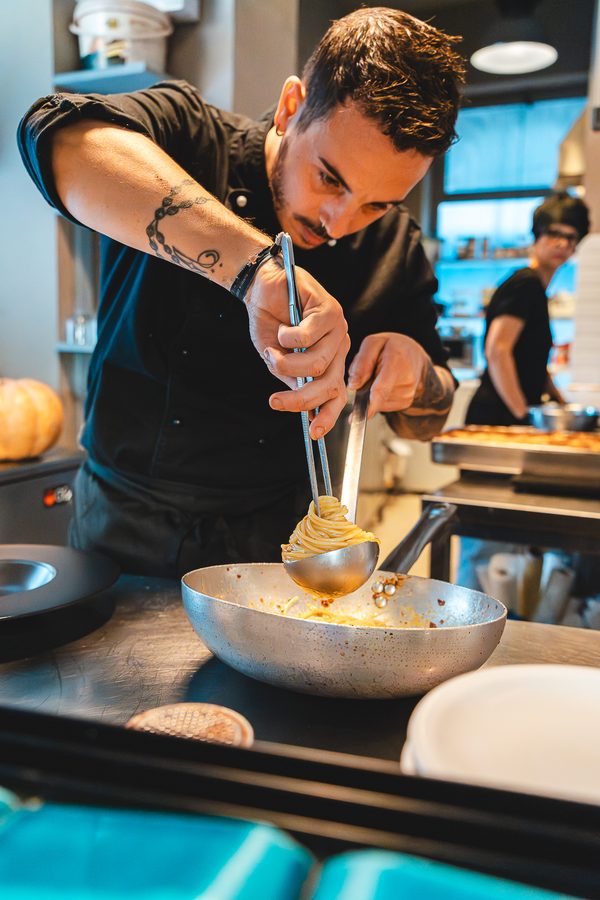 Il cuoco impiatta al bancone della cucina