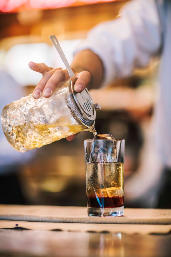Un barista versa un drink in un bicchiere col ghiaccio