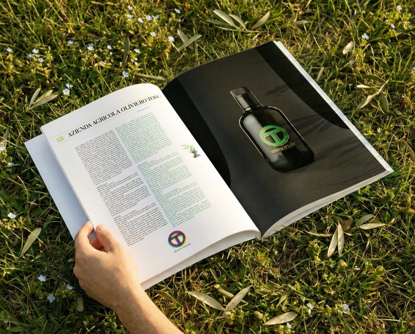 Una mano sfoglia il libro aperto sull’erba, alla pagina di una bottiglia