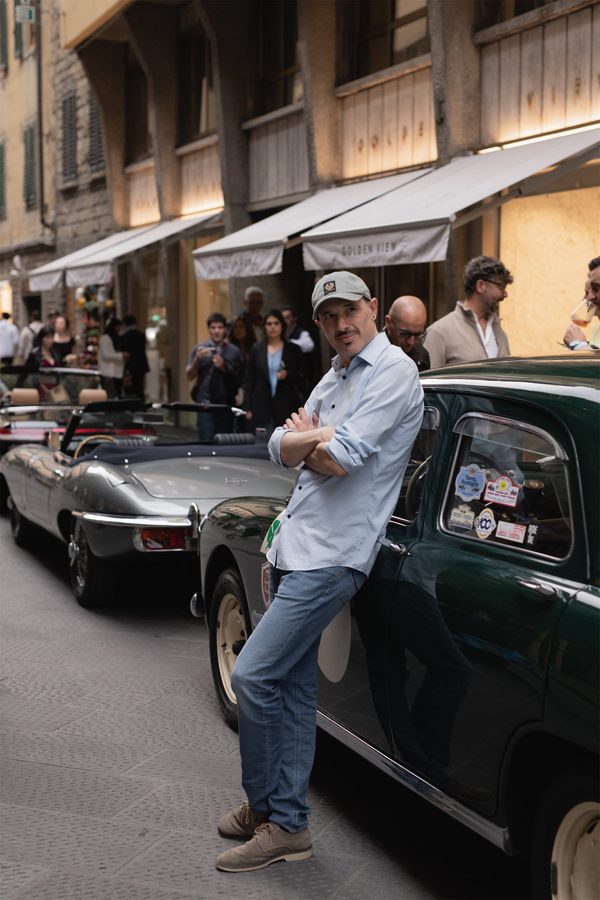 Un ospite in cappello accanto a un’auto d’epoca sul lungarno