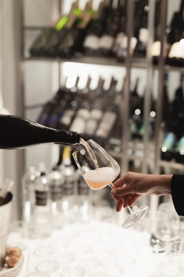 Un bicchiere di vino bianco versato davanti alle bottiglie