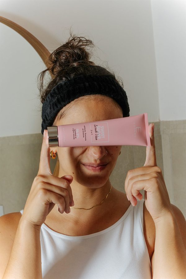 Una ragazza tiene un tubetto rosa Essere Bio davanti agli occhi