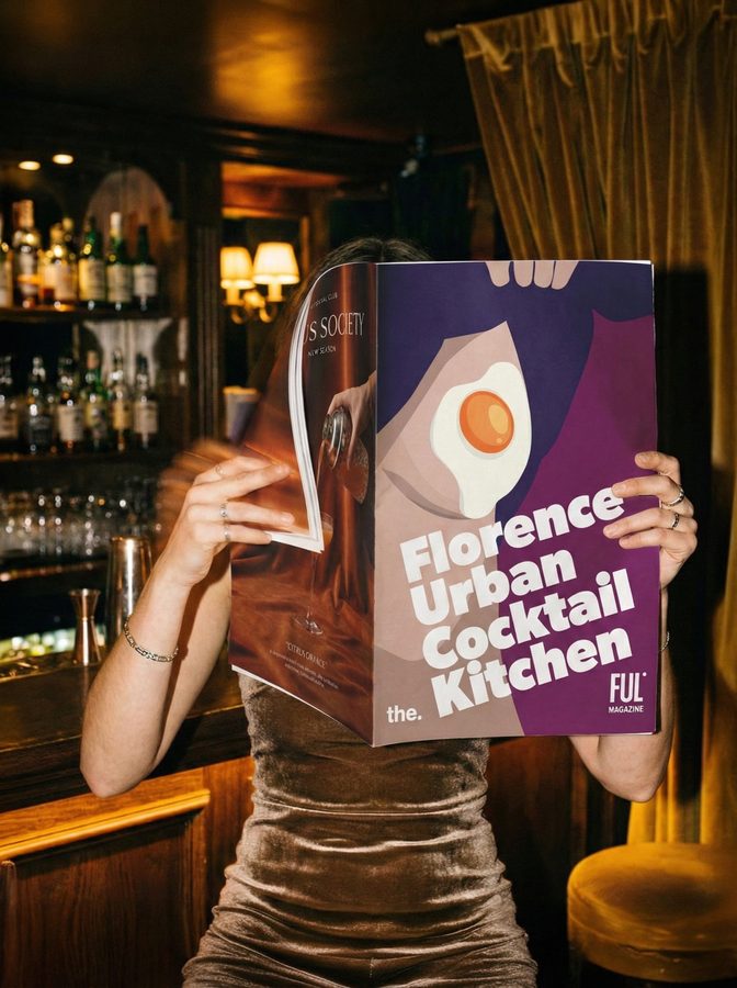 Una ragazza in un cocktail bar tiene la copertina di F.U.C.K. Magazine