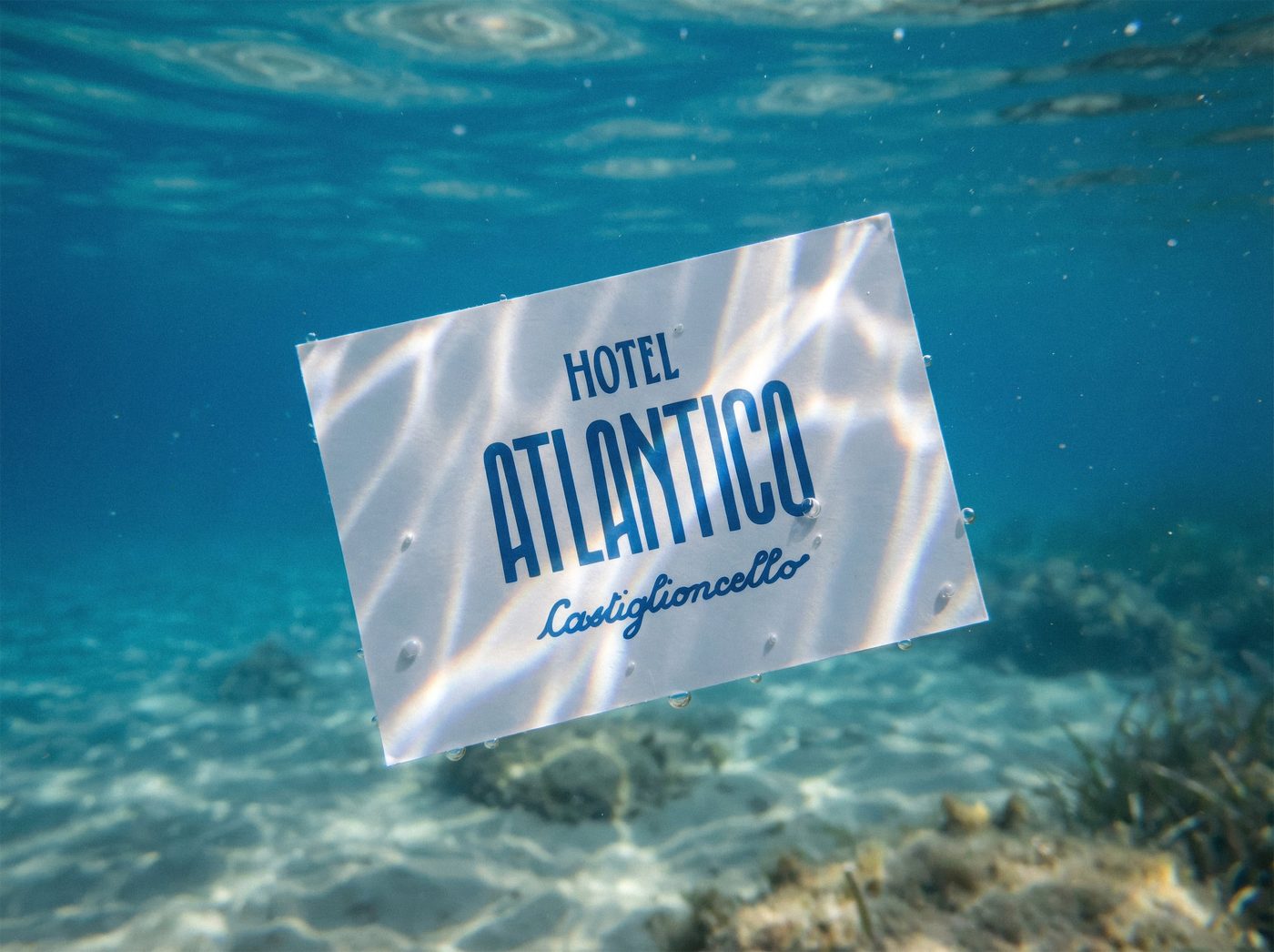 Il biglietto dell’Hotel Atlantico sott’acqua, sulla sabbia del fondale