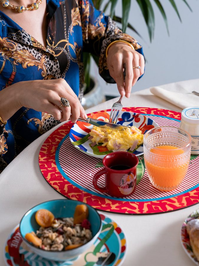 Due mani servono la colazione su piatti colorati