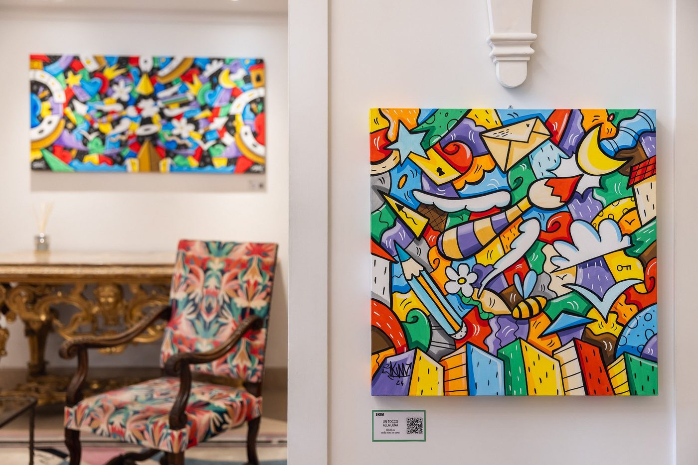 I quadri coloratissimi di SKIM appesi all’Hotel Savoy, per la mostra Oltre il traguardo