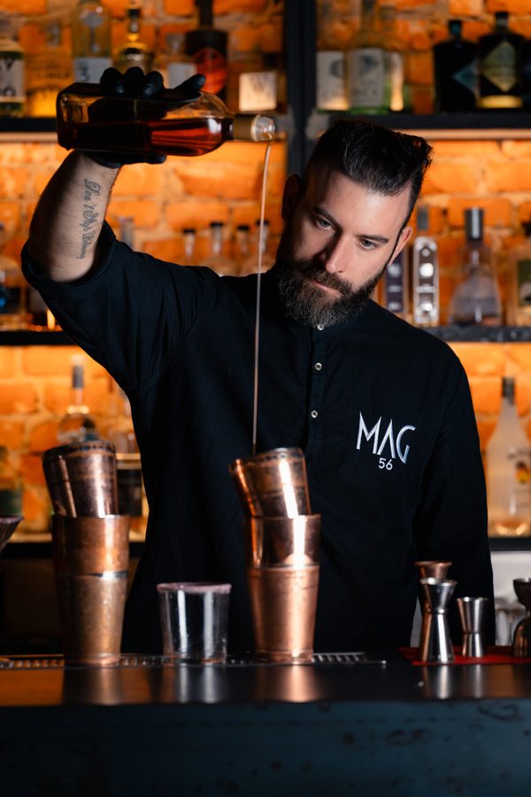 Il barman di MAG 56 versa un drink al bancone
