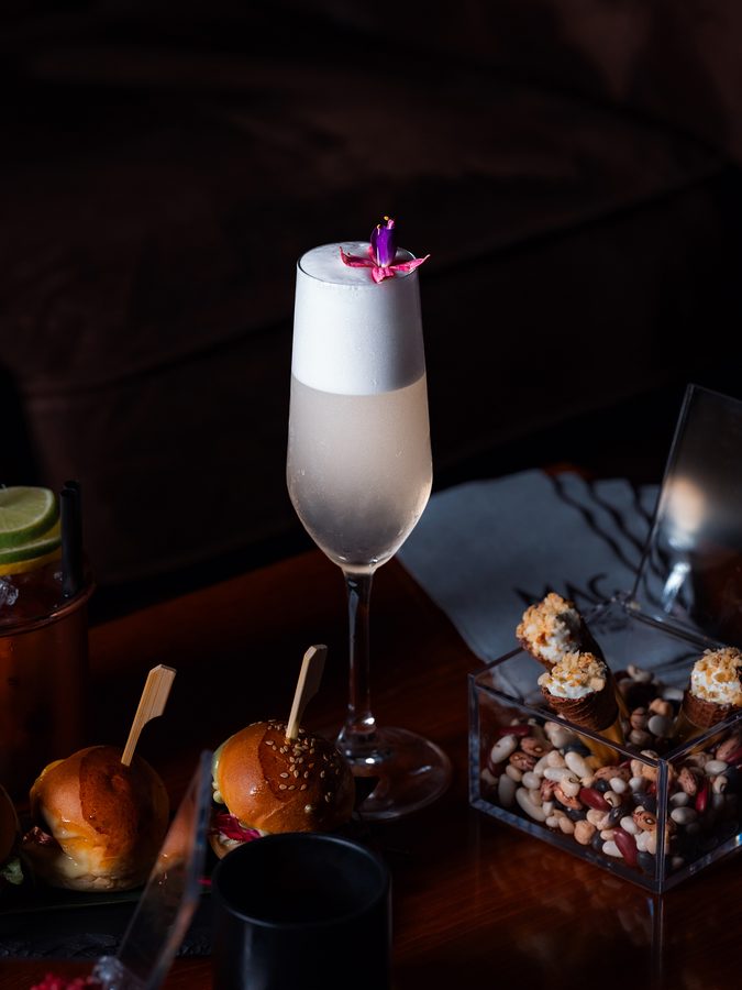 Un cocktail bianco con un fiore, fra i piatti
