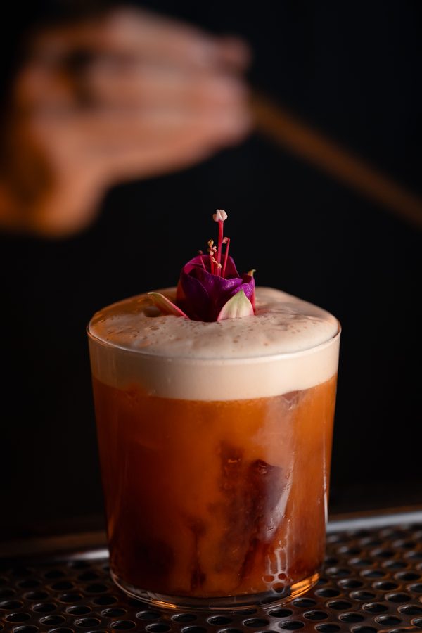 Un cocktail con la schiuma e un fiore rosa