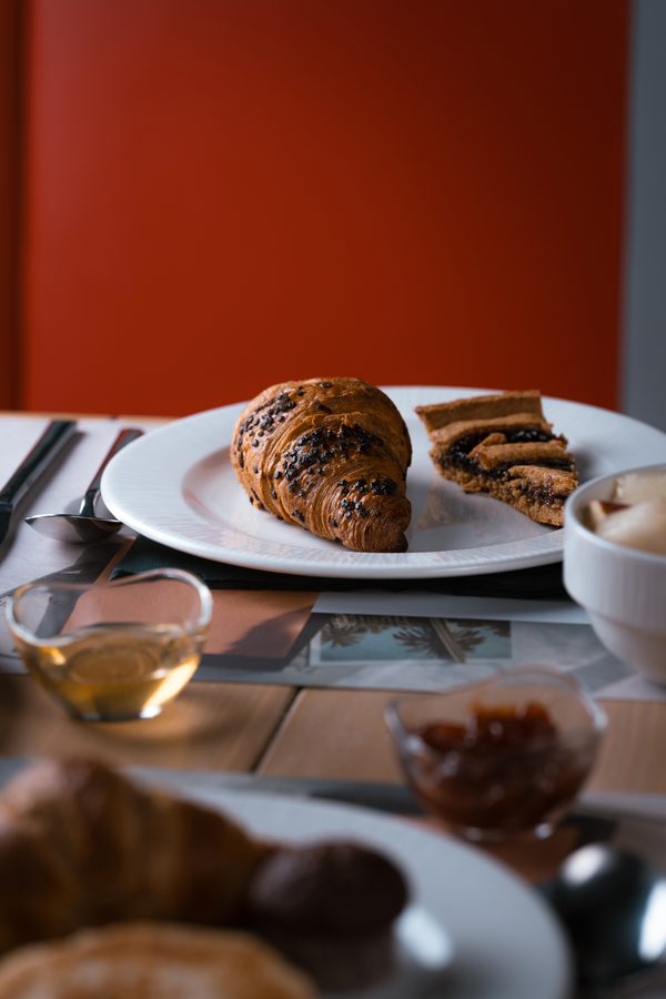 Una colazione con cornetti su un tavolo, davanti alla parete rossa
