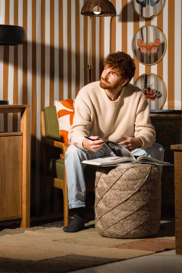 Un ragazzo legge seduto su un pouf
