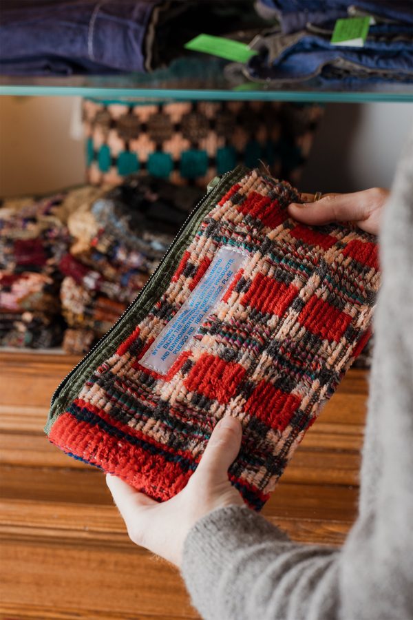 Due mani aprono una pochette rossa e nera Puebco