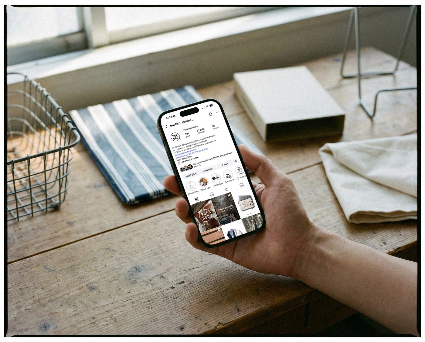 Un telefono coi contenuti di Puebco Europe, su un tavolo accanto a un telo a righe