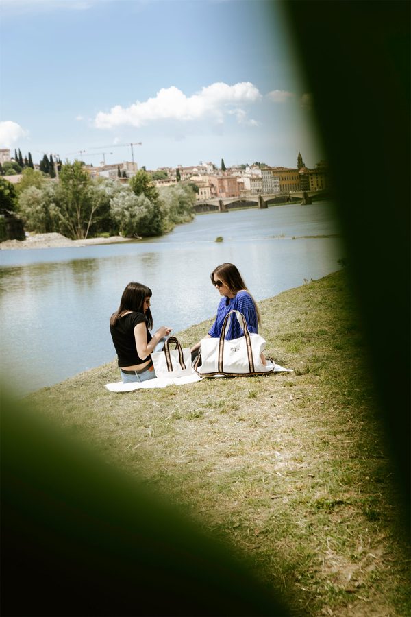 Due persone sedute sul prato in riva a un lago, fra le foglie