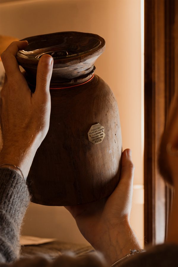 Due mani tengono un vaso di legno scuro
