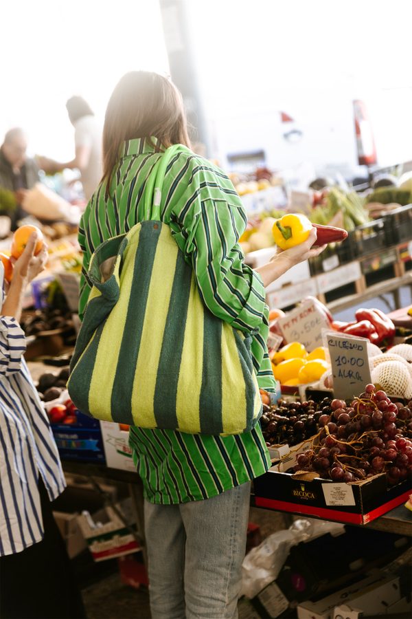 Una borsa a righe verdi Puebco al mercato, fra la frutta